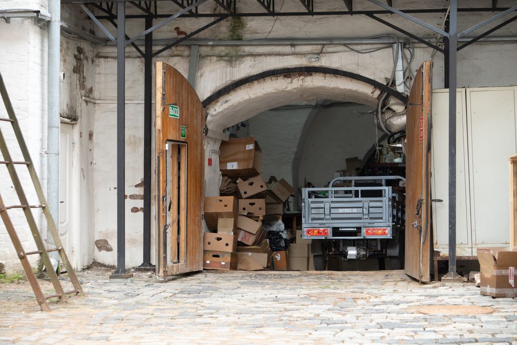 Hot tub Removal 1 Warehouse entrance with cardboard boxes and open wooden doors, a vehicle partially visible.